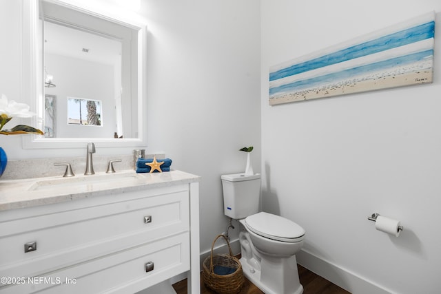 half bathroom featuring vanity, toilet, wood finished floors, and baseboards