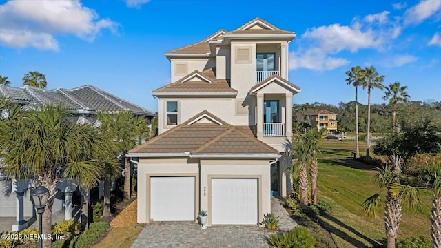 view of front of home featuring stucco siding, a tiled roof, decorative driveway, and a front yard