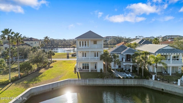 back of property featuring a yard, a water view, a balcony, and a residential view