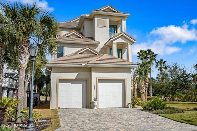 mediterranean / spanish home with a tile roof, a balcony, decorative driveway, and stucco siding