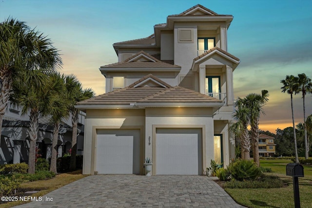 view of front of home with decorative driveway, a garage, and stucco siding