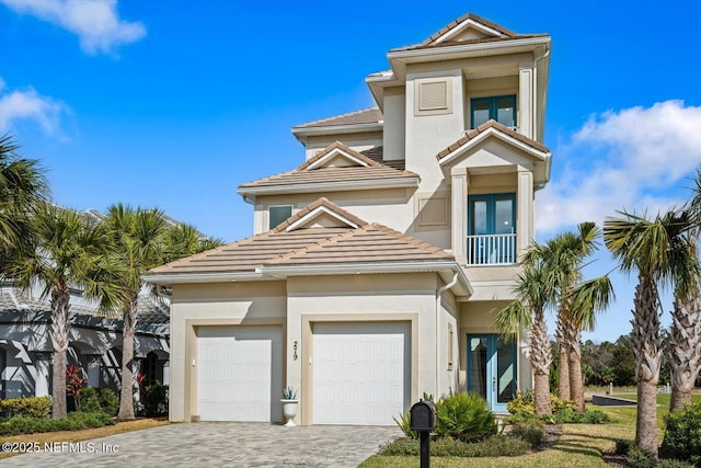 view of front of property with stucco siding, decorative driveway, an attached garage, and a tile roof