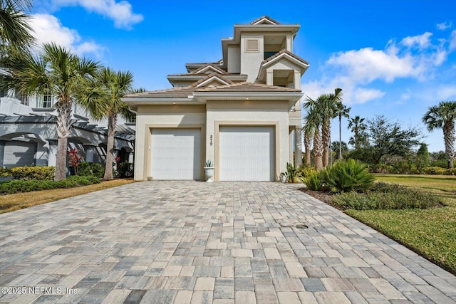 prairie-style house featuring a tile roof, decorative driveway, a garage, and stucco siding