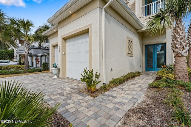 property entrance featuring stucco siding, an attached garage, and french doors