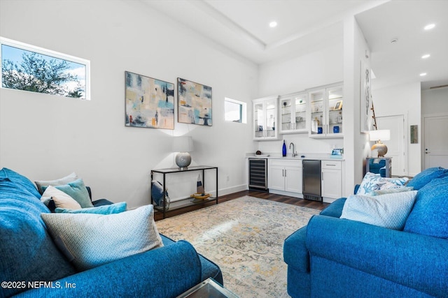 living room featuring dark wood-type flooring, baseboards, beverage cooler, indoor wet bar, and recessed lighting