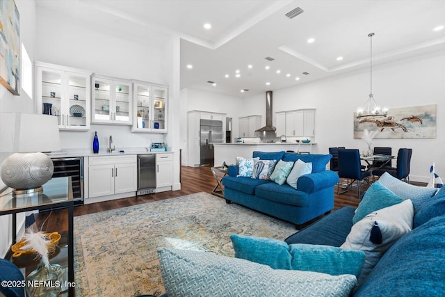 living area featuring visible vents, beverage cooler, indoor wet bar, a notable chandelier, and dark wood-style flooring