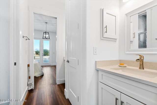 bathroom featuring vanity, hardwood / wood-style flooring, baseboards, and ensuite bath