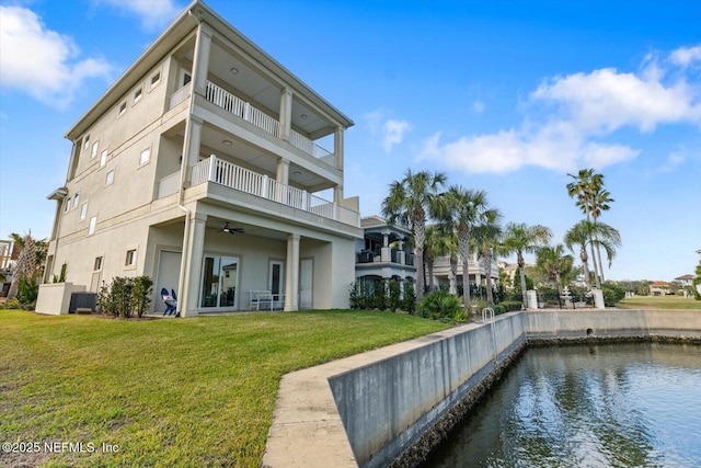 rear view of property featuring central air condition unit, a water view, stucco siding, a yard, and a balcony