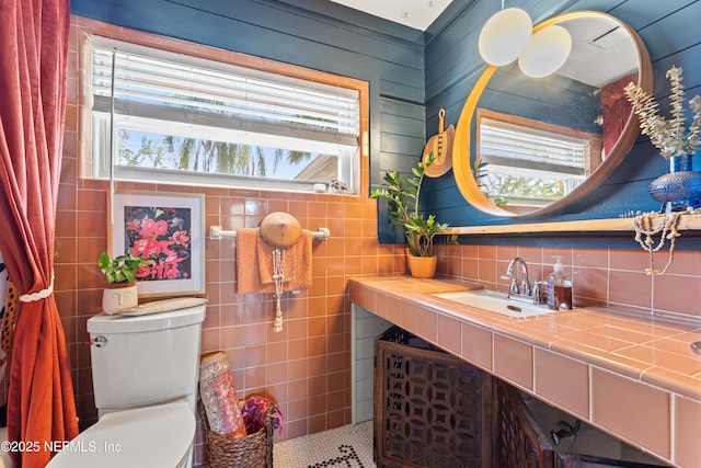 bathroom with plenty of natural light, vanity, toilet, and tile walls