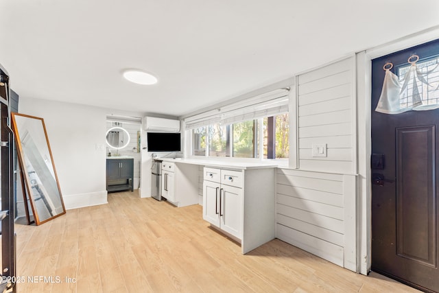 kitchen with baseboards, light countertops, light wood-type flooring, and white cabinets