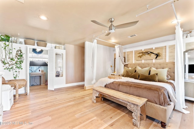 bedroom with ceiling fan, wood finished floors, and visible vents