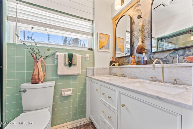 full bathroom with toilet, double vanity, visible vents, and a sink