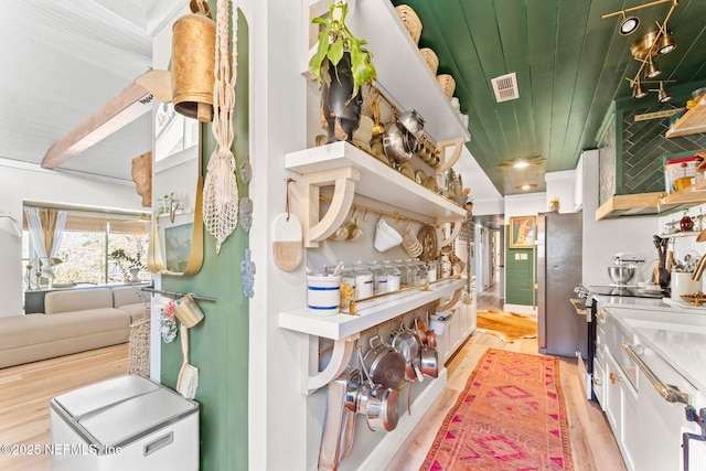 kitchen with light wood-style flooring, electric range, wood ceiling, visible vents, and white cabinetry