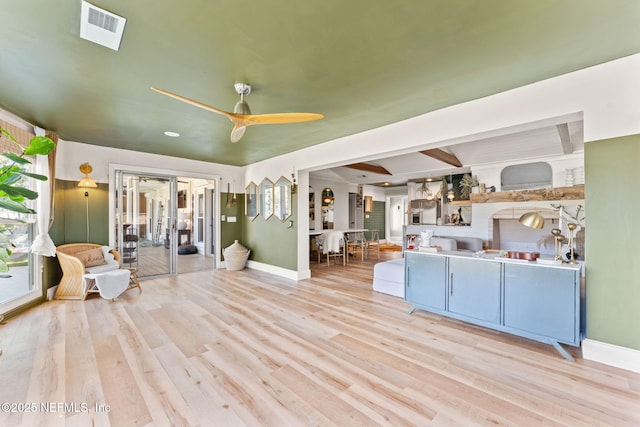 unfurnished living room featuring baseboards, ceiling fan, visible vents, and wood finished floors