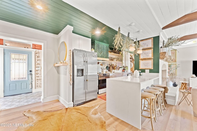 kitchen with a peninsula, light wood-type flooring, a kitchen bar, and appliances with stainless steel finishes