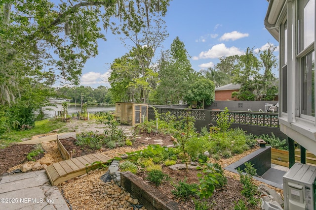 view of yard with a water view, fence, and a garden