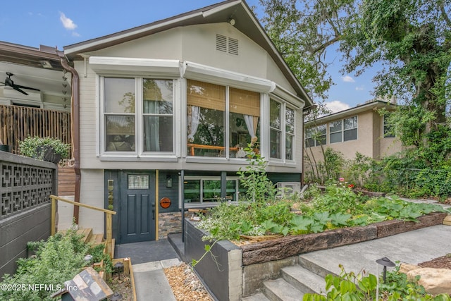 view of front of house featuring a sunroom, stone siding, and a vegetable garden