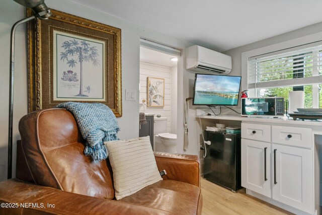 sitting room featuring light wood-type flooring and a wall unit AC