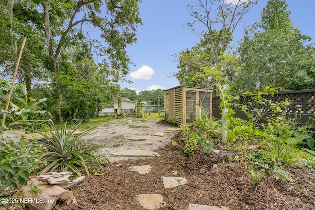 view of yard featuring fence, a greenhouse, and an outdoor structure