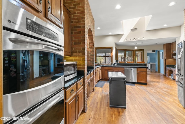 24620 Deer Trace Dr, Ponte Vedra Beach, FL 32082 - kitchen with brown cabinetry, a peninsula, light wood-style floors, appliances with stainless steel finishes, and a center island