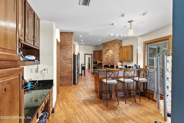 24620 Deer Trace Dr, Ponte Vedra Beach, FL 32082 - kitchen featuring visible vents, light wood finished floors, a peninsula, freestanding refrigerator, and a kitchen bar
