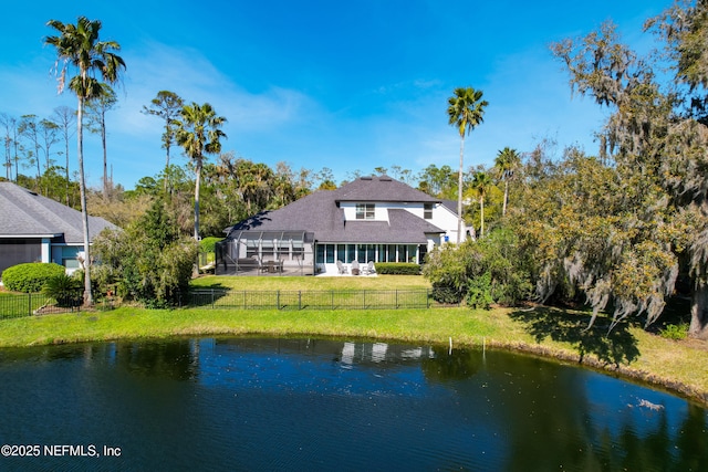 back of property featuring a shingled roof, a water view, a lawn, glass enclosure, and a fenced backyard