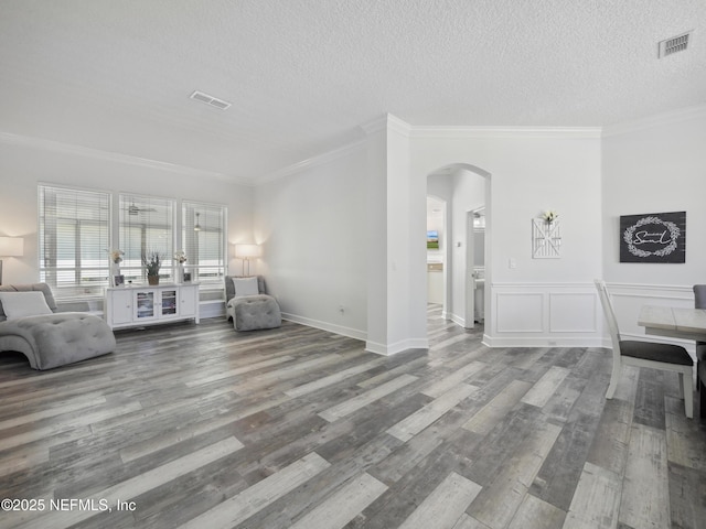 unfurnished living room with visible vents, arched walkways, a textured ceiling, and wood finished floors