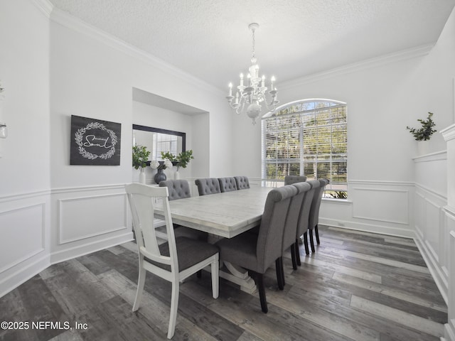 dining room with a textured ceiling, an inviting chandelier, dark wood-style flooring, and crown molding