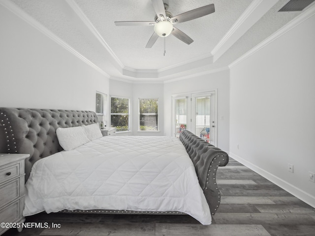 bedroom featuring visible vents, crown molding, baseboards, wood finished floors, and a raised ceiling