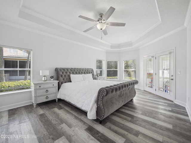 bedroom with ornamental molding, access to outside, a tray ceiling, baseboards, and dark wood-style flooring