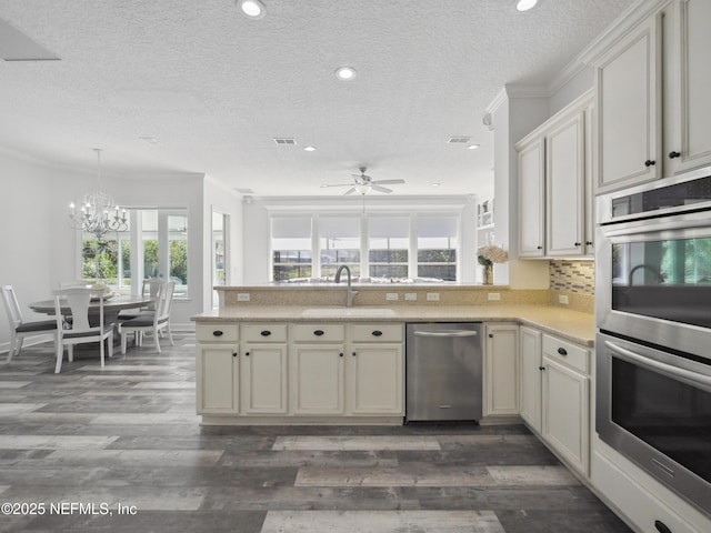 kitchen featuring ornamental molding, a sink, tasteful backsplash, appliances with stainless steel finishes, and a peninsula