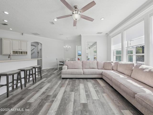 living room with visible vents, ornamental molding, a textured ceiling, wood finished floors, and arched walkways