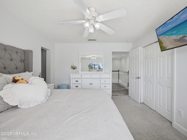 bedroom featuring visible vents, a ceiling fan, a textured ceiling, a closet, and light colored carpet