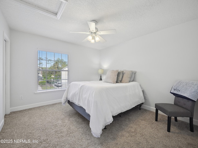 bedroom with ceiling fan, baseboards, attic access, carpet floors, and a textured ceiling