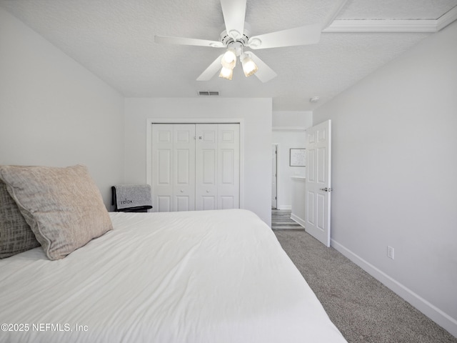 carpeted bedroom featuring a ceiling fan, baseboards, visible vents, a closet, and a textured ceiling