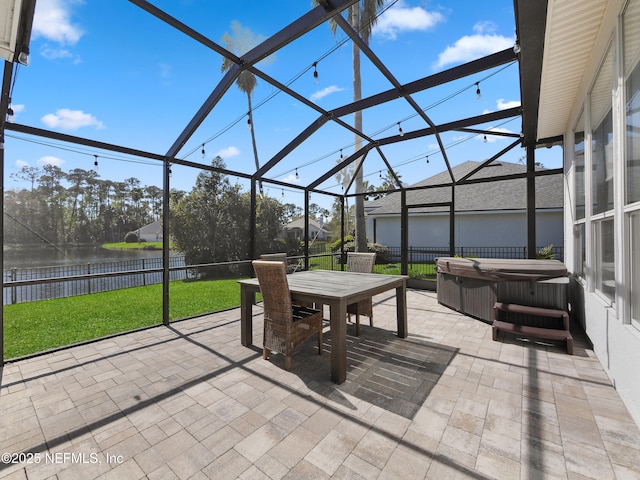 view of patio featuring glass enclosure, fence, a water view, and a hot tub