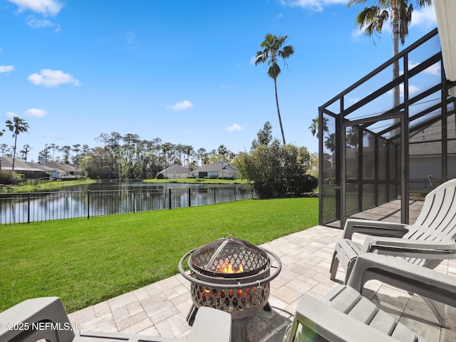 view of patio featuring a lanai, an outdoor fire pit, fence, and a water view