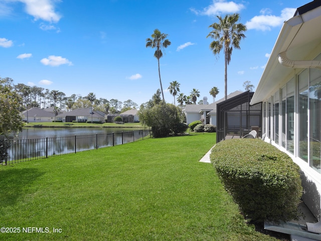 view of yard with glass enclosure, a water view, a residential view, and fence