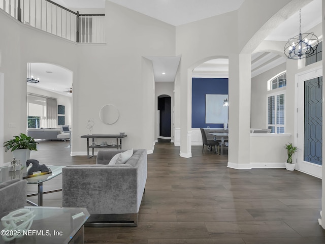 297 S Hampton Club Way, Saint Augustine, FL 32092 - living room featuring baseboards, arched walkways, dark wood-type flooring, a high ceiling, and an inviting chandelier