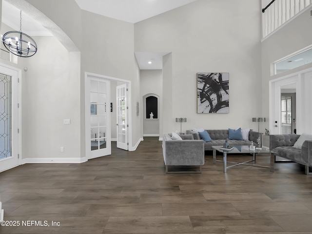 297 S Hampton Club Way, Saint Augustine, FL 32092 - living room featuring an inviting chandelier, arched walkways, dark wood-style floors, and a high ceiling