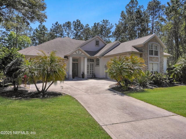 297 S Hampton Club Way, Saint Augustine, FL 32092 - view of front of property with a front yard, stone siding, roof with shingles, curved driveway, and stucco siding