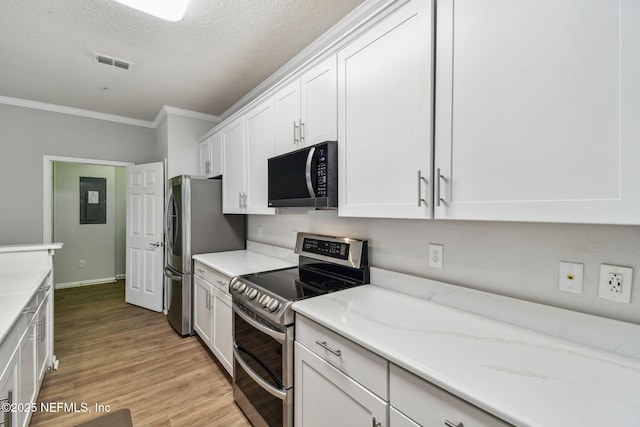 kitchen with stainless steel appliances, visible vents, white cabinets, ornamental molding, and light wood-type flooring