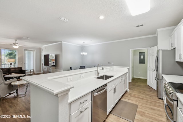 kitchen featuring light wood finished floors, white cabinets, appliances with stainless steel finishes, open floor plan, and a sink