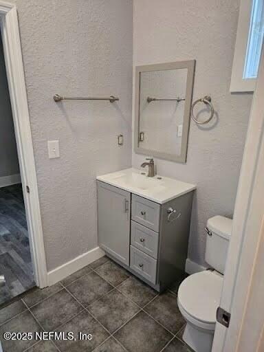 bathroom featuring toilet, vanity, and baseboards