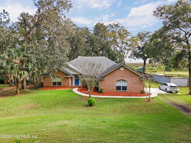 view of front of property with driveway, a front yard, and brick siding