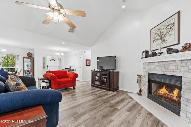 living room featuring a fireplace, visible vents, wood finished floors, baseboards, and ceiling fan with notable chandelier