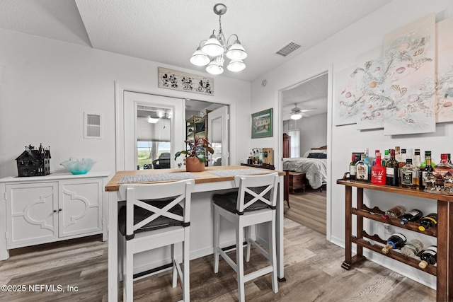 dining room featuring light wood-type flooring, visible vents, and an inviting chandelier