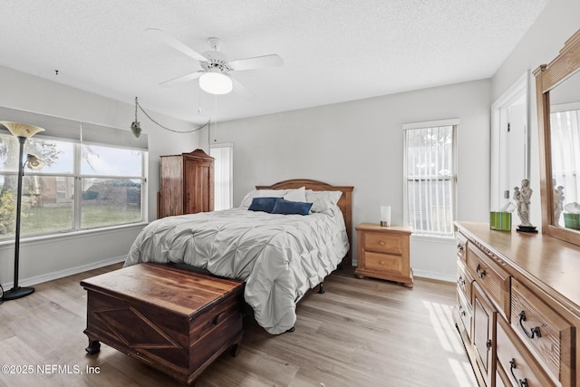 bedroom featuring a textured ceiling, baseboards, a ceiling fan, and light wood-style floors