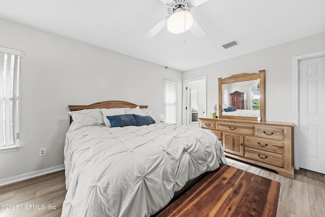 bedroom with multiple windows, wood finished floors, visible vents, and baseboards