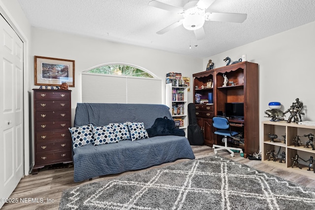 interior space featuring a textured ceiling, a ceiling fan, and wood finished floors